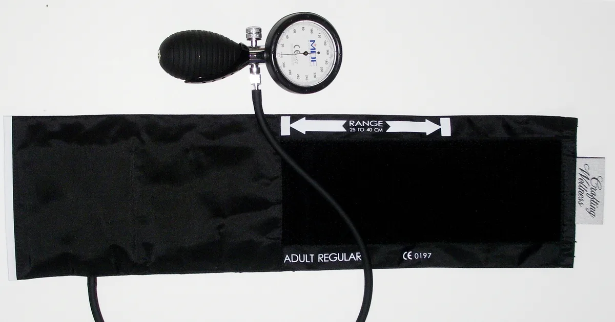 An aneroid sphygmomanometer blood pressure gauge and cuff on a white background.