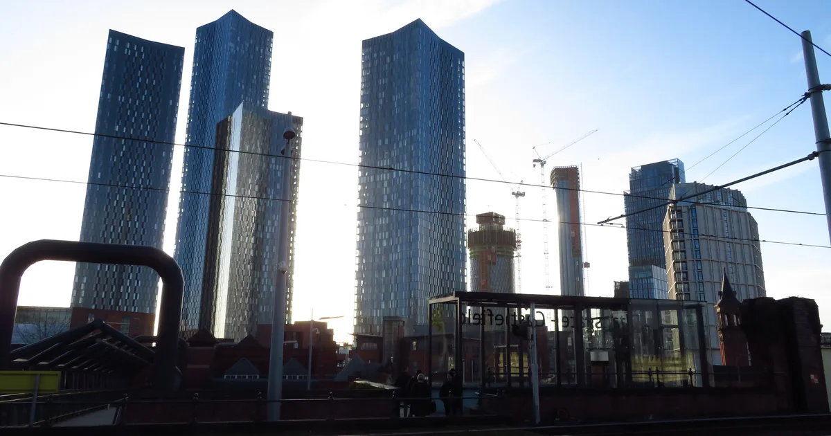 Deansgate Square's residential tower blocks in Manchester, with construction cranes visible between them.