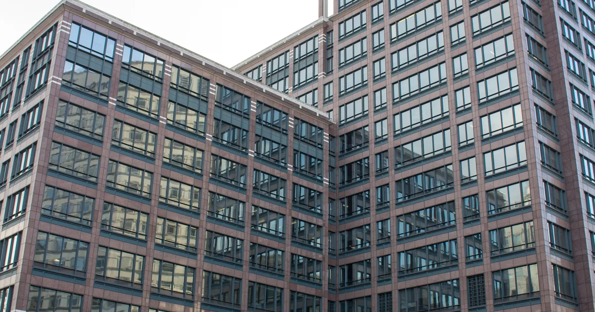 25 Cabot Square, a tall glass office tower in Canary Wharf, London, photographed from the square below.