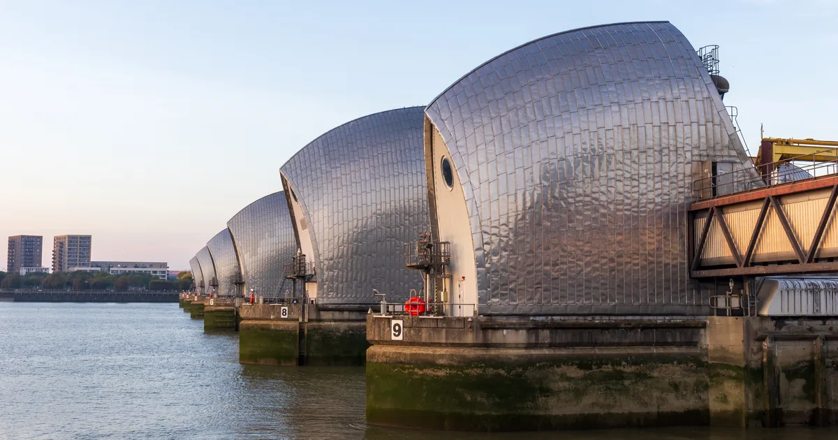 The Thames Barrier, London, viewed from the south bank, showing its silver steel gates spanning the river.