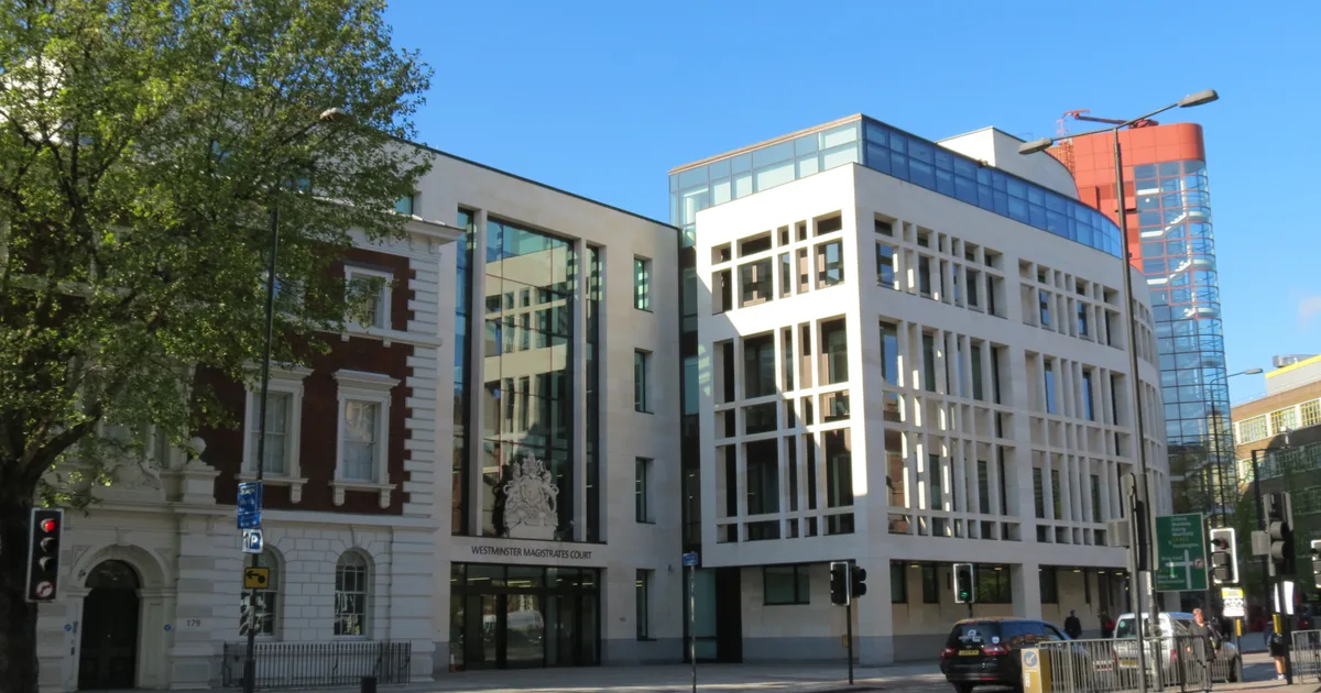Westminster Magistrates' Court, a modern stone and glass court building with the Royal Arms carved above the entrance, photographed from the street.