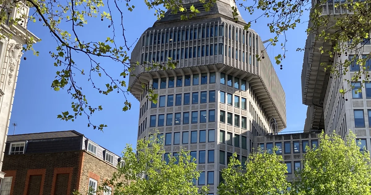 102 Petty France, Westminster, London, the brutalist Ministry of Justice headquarters building, viewed from street level through tree branches.