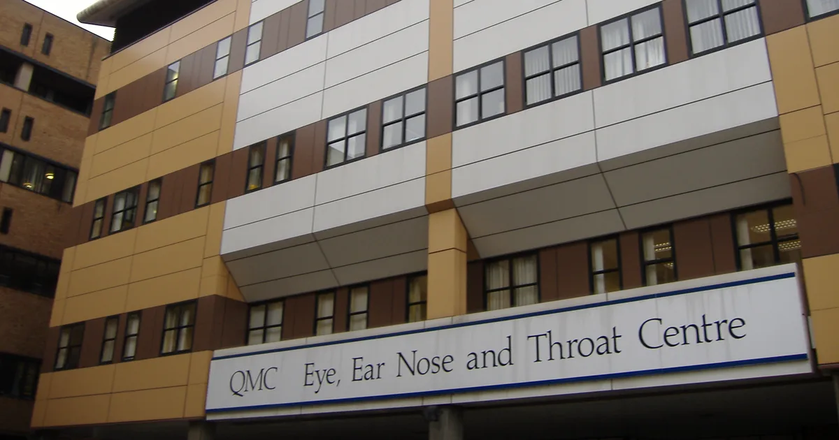The exterior of Queen's Medical Centre in Nottingham, showing a modern cladded facade and a sign reading QMC Eye, Ear Nose and Throat Centre.