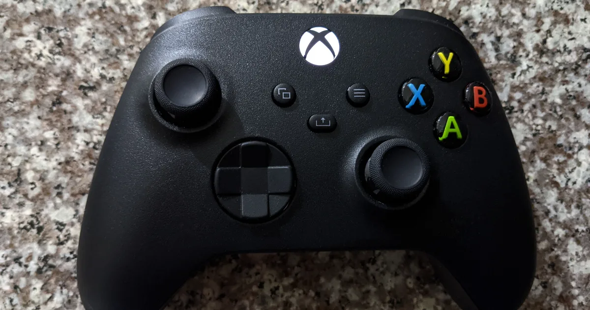 A black Xbox Series wireless controller resting on a granite surface.