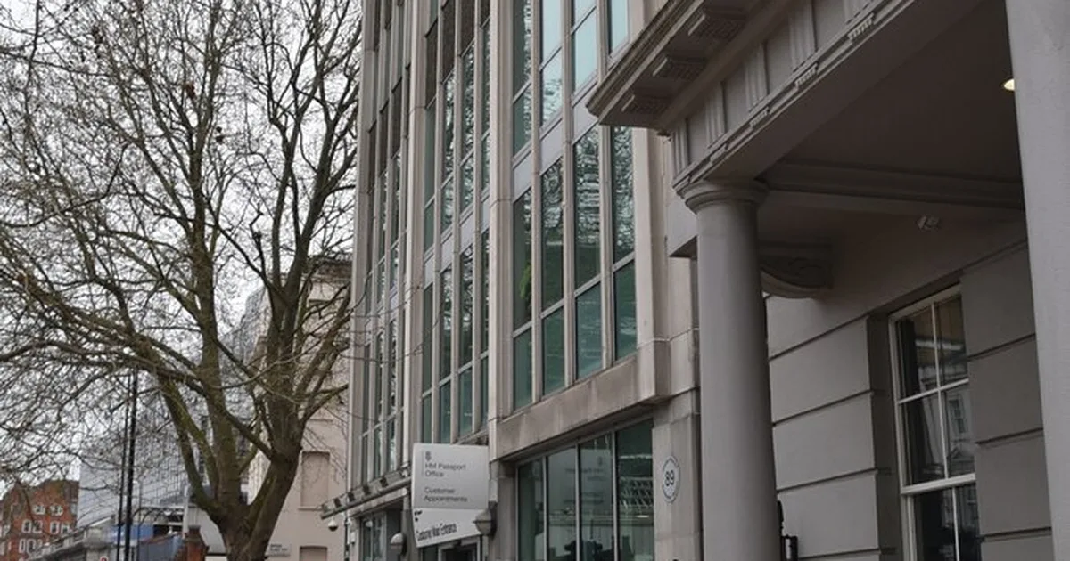 The entrance to HM Passport Office on Belgrave Road, London, with a sign reading 'HM Passport Office, Customer Appointments' beside the glass doors.