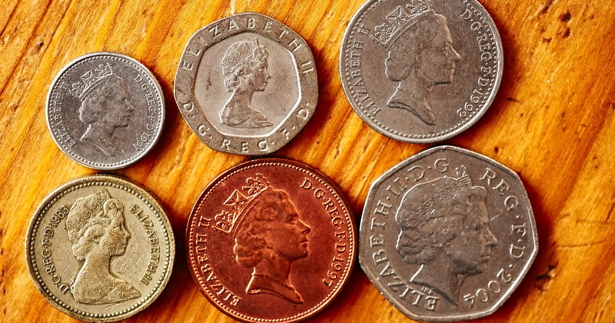 British pound sterling coins and a banknote bearing Queen Elizabeth II's portrait, fanned out on a flat surface.