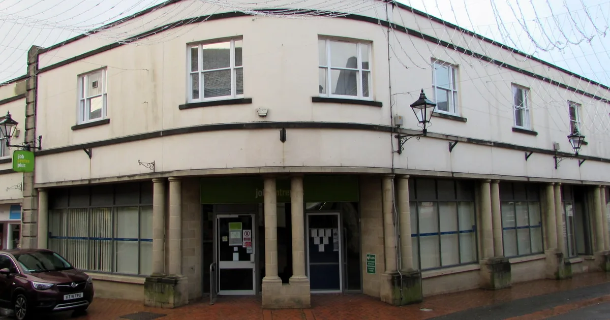 A Jobcentre Plus branch on a town-centre corner, with stone columns at the entrance and the green Jobcentre Plus sign above the door.