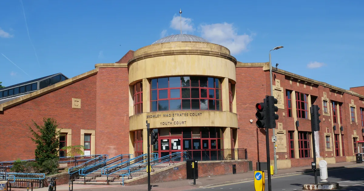 Bromley Magistrates Court and Youth Court, a brick building with a curved glass and stone entrance, photographed from the street under a clear blue sky.