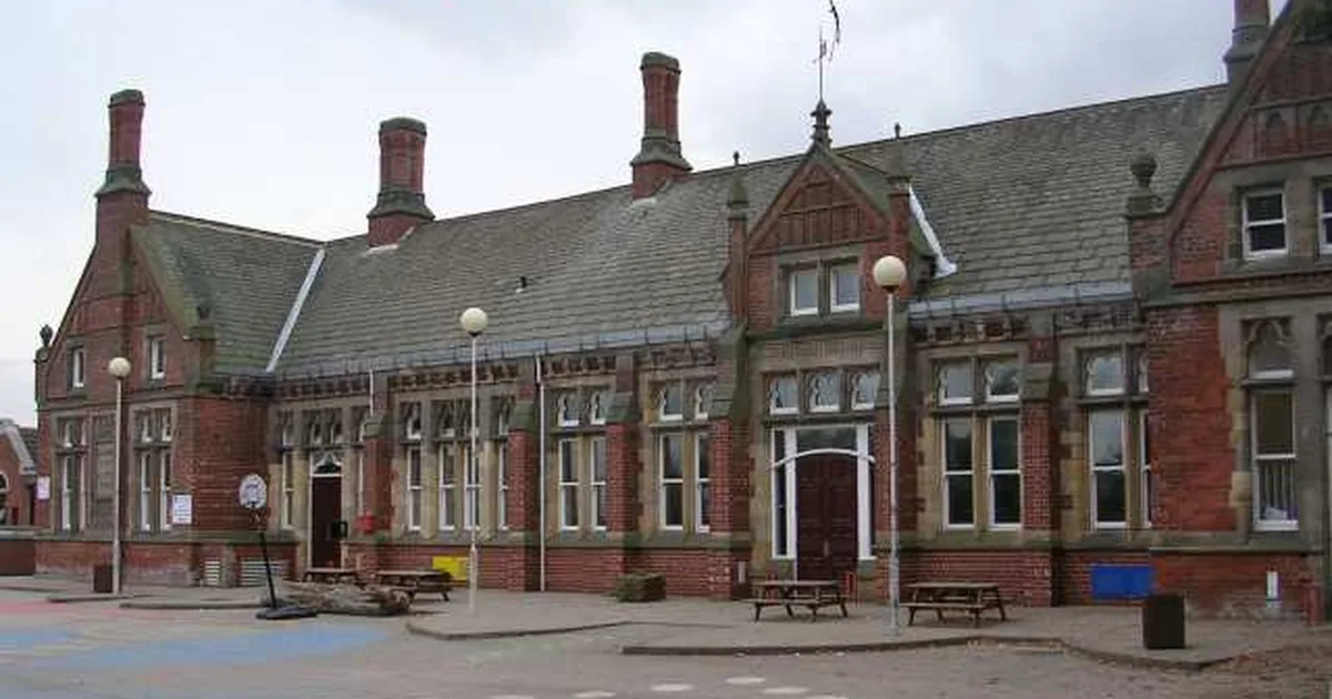 Chapel Allerton Primary School, a Victorian red-brick board school in Leeds, seen across its empty playground with picnic benches in the foreground.