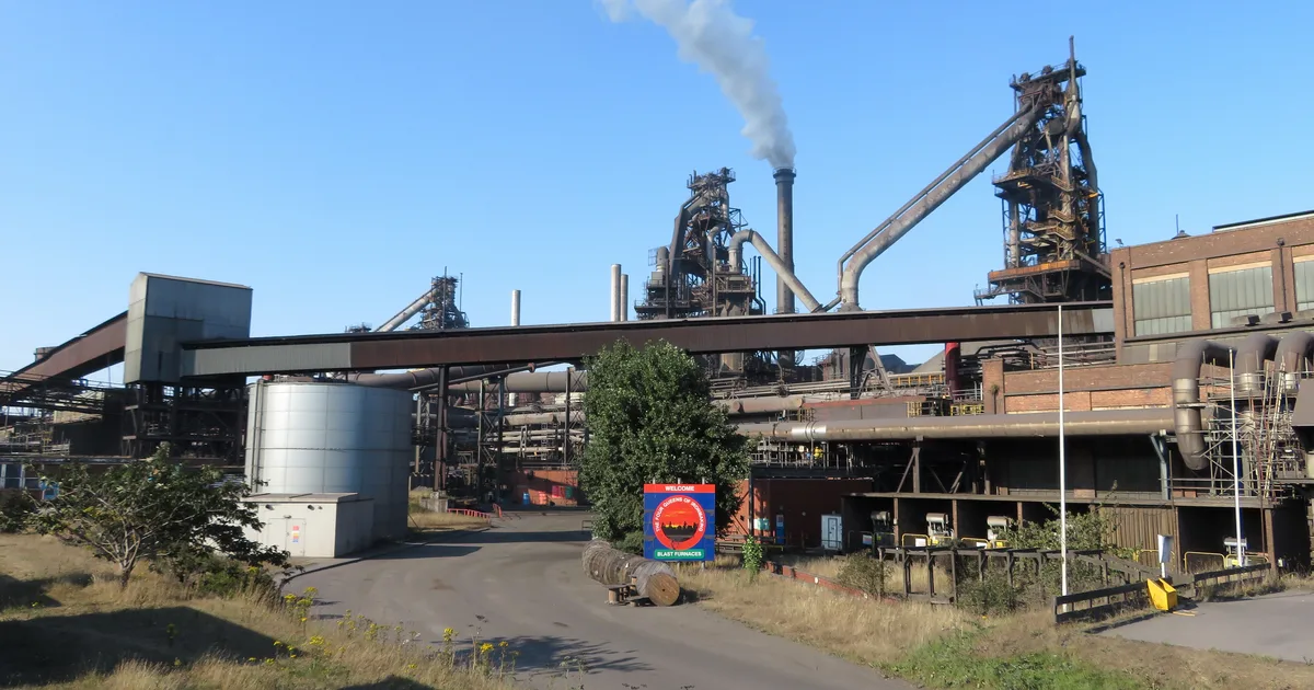 Blast furnaces and chimneys at British Steel's Scunthorpe works, with steam rising against a clear sky.