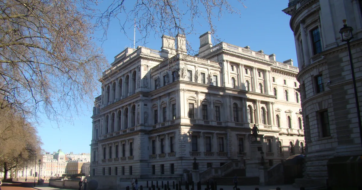 The HM Treasury building on Horse Guards Road, London, photographed from street level against a clear blue sky.