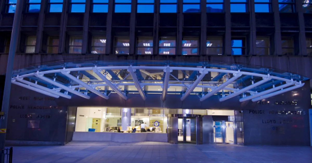 The illuminated glass canopy and signage reading West Midlands Police Headquarters, Lloyd House, over the entrance of the force's Birmingham headquarters at night.